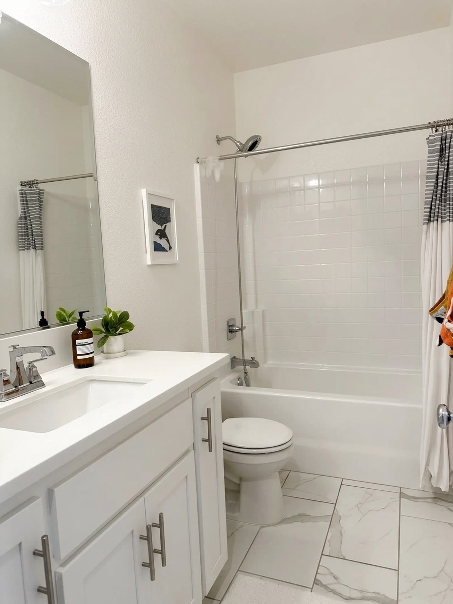 A second bathroom, finished in white tile.